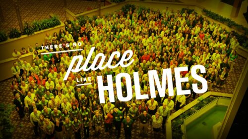 a group of Holmes Murphy employees with text 'there's no place like Holmes' across the top