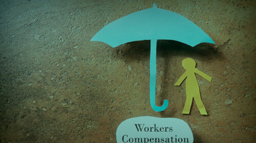 A paper cut out of an umbrella and person with 'workers compensation' as a puddle under the umbrella.