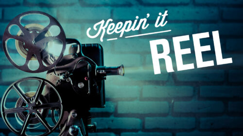 A film projector with the text 'Keepin' it Reel' on a brick wall