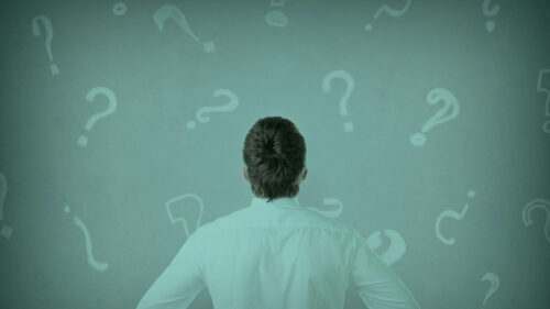 A person staring confused at a wall with question marks.