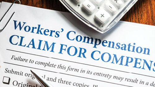 A workers compensation claim form with a pen and calculator on a desk