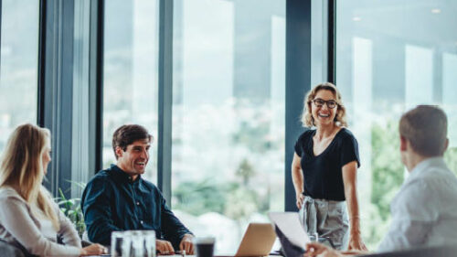 Multi-generational business professionals talking and laughing around a conference table