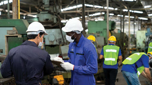 manufacturing workers wearing protective equipment as they work.