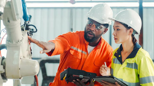 Two diverse industrial workers working together to examine equipment.