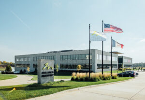 Holmes Murphy office in Waukee with a bright blue sky, green grass and the Holmes Murphy, USA, and Iowa flags blowing in the wind.