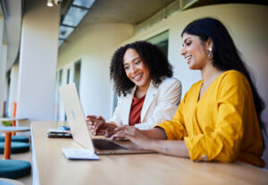 Two women talking over a computer