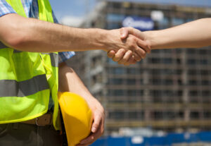 To construction workers shaking hands on a jobsite.