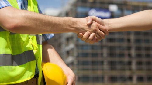 To construction workers shaking hands on a jobsite.