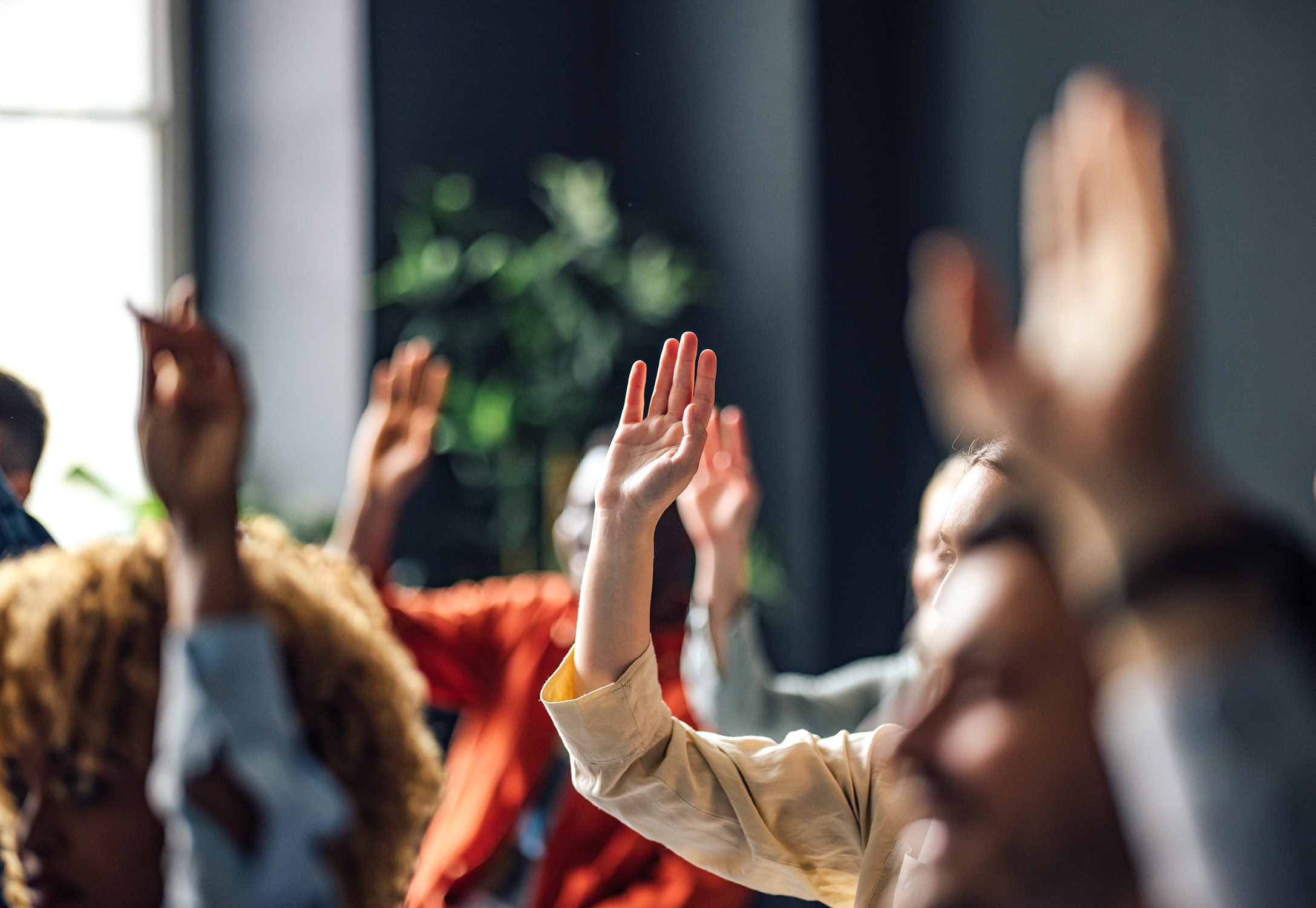 A group of professionals raising their hand.