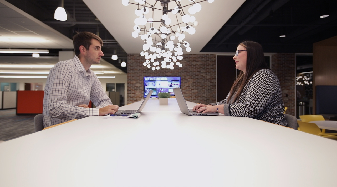 Haleigh Mason and coworker talking at a table.