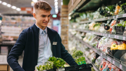 A grocery employee stocking vegetables