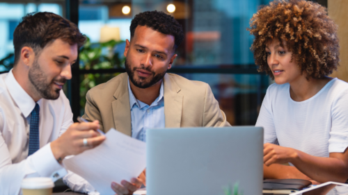 Three people discussing insurance around a laptop