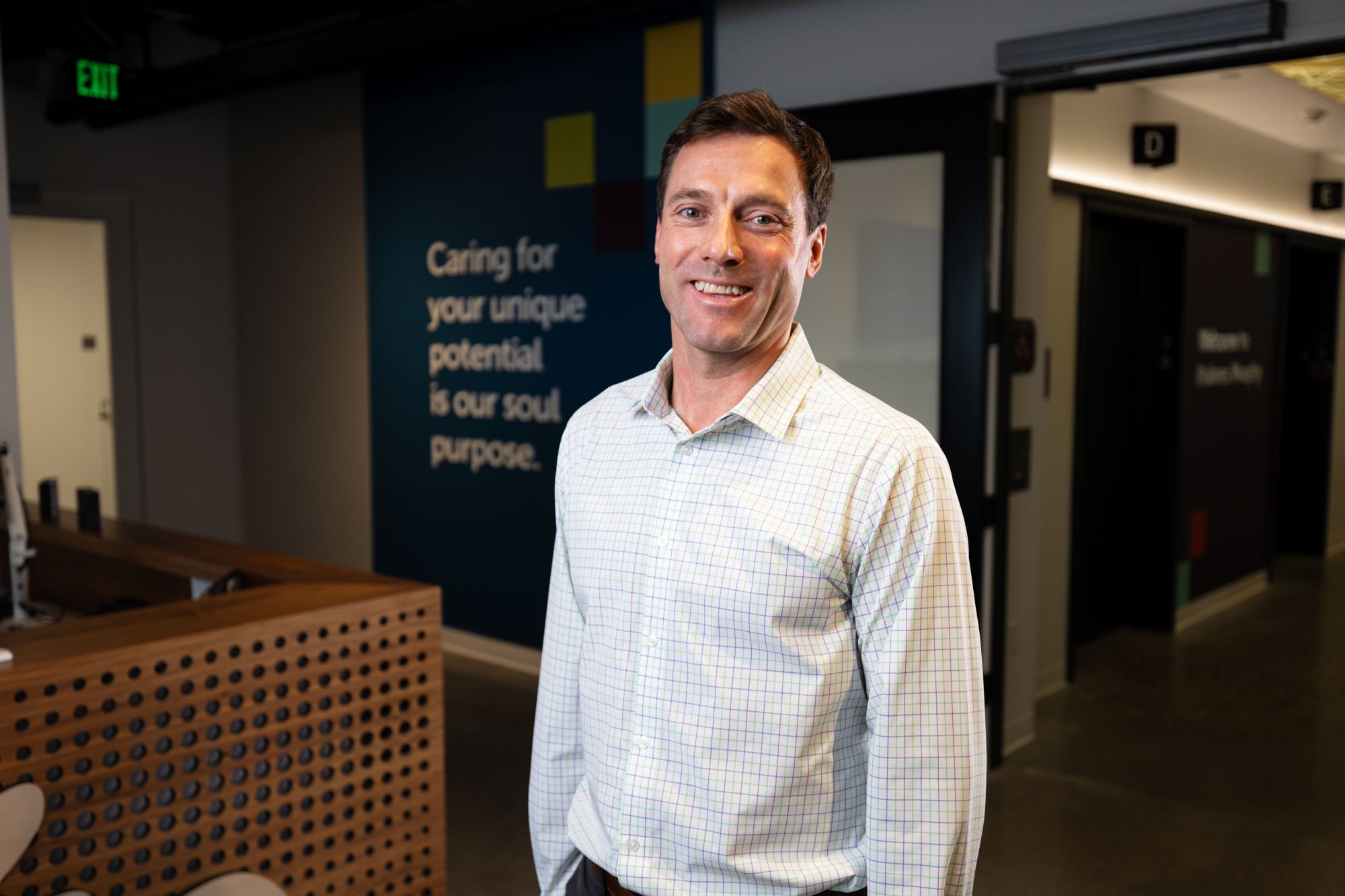 Bryce Craig in white collar button down smiling.