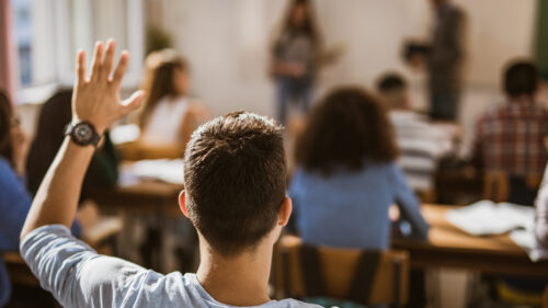 A young man raising his hand in class.