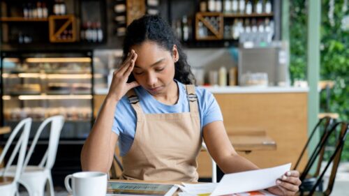 A small business owner looks stressed while reviewing bills
